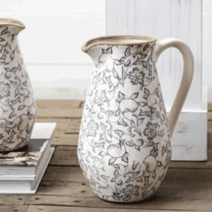 Elegant ceramic pitcher with butterfly design on wooden table.
